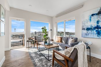 an open living room with a view of the city and a couch and chairs  at Oslo, Seattle, 98102
